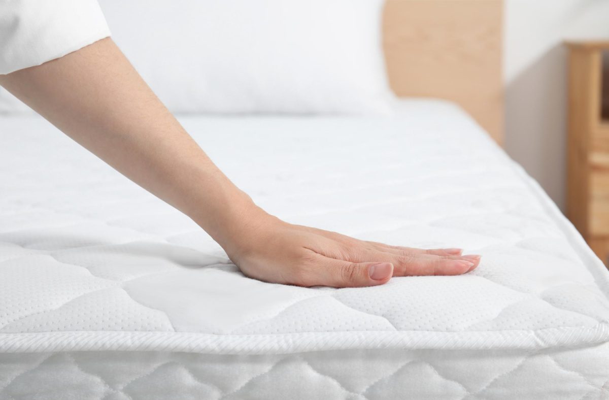 Femme touchant un matelas blanc afin d'en vérifier la qualité.